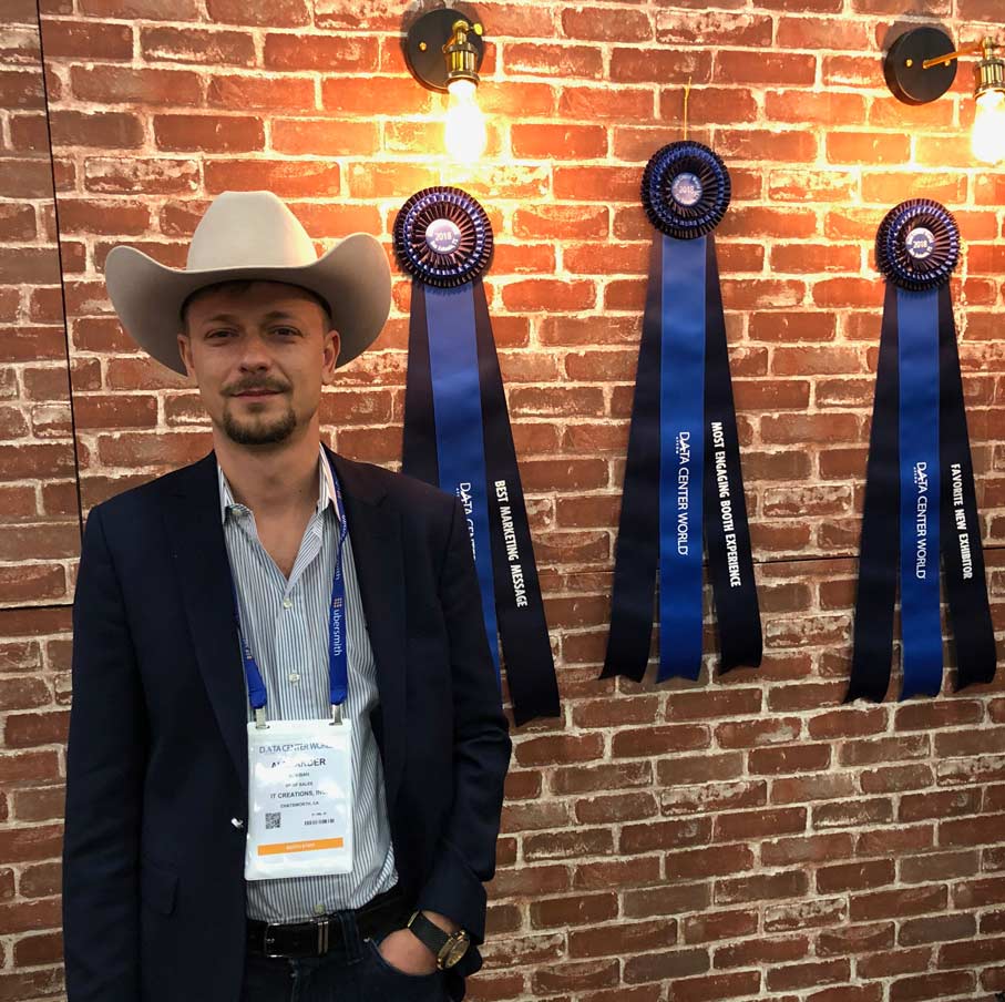 Alex at Data Center World 2018 with a 10-gallon Hat and awards